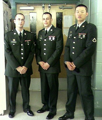 Daniel Kekipi standing in army green dress uniform alongside two soldiers