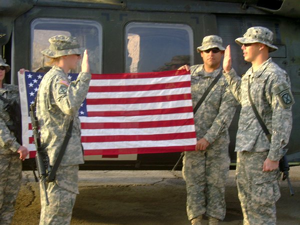 Daniel Kekipi raising right hand during reenlistment ceremony in front of helicopter