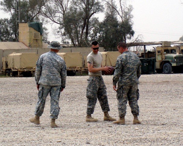Daniel Kekipi and fellow soldiers holding a football outdoors on base in Iraq