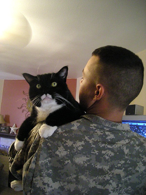 Daniel Kekipi holding black and white cat Keiko on his shoulder
