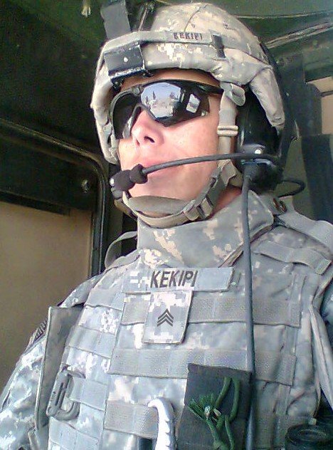 Daniel Kekipi wearing full helmet, combat vest, and communications headset inside vehicle