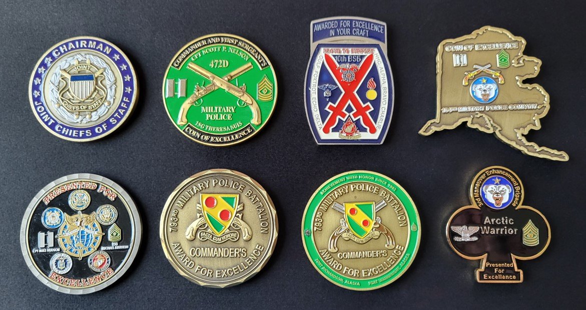 Eight military challenge coins displayed on flat black background